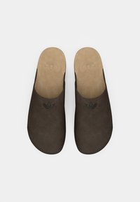 Browni natikači na slip-on z gladko teksturo, ki imajo logo na zgornjem delu in kontrastno bež podplat. Ravna, minimalistična zasnova.
