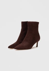 Botas de ante marrón hasta el tobillo con puntera puntiaguda y tacón delgado, con un diseño elegante y una cremallera en la parte trasera para el cierre.