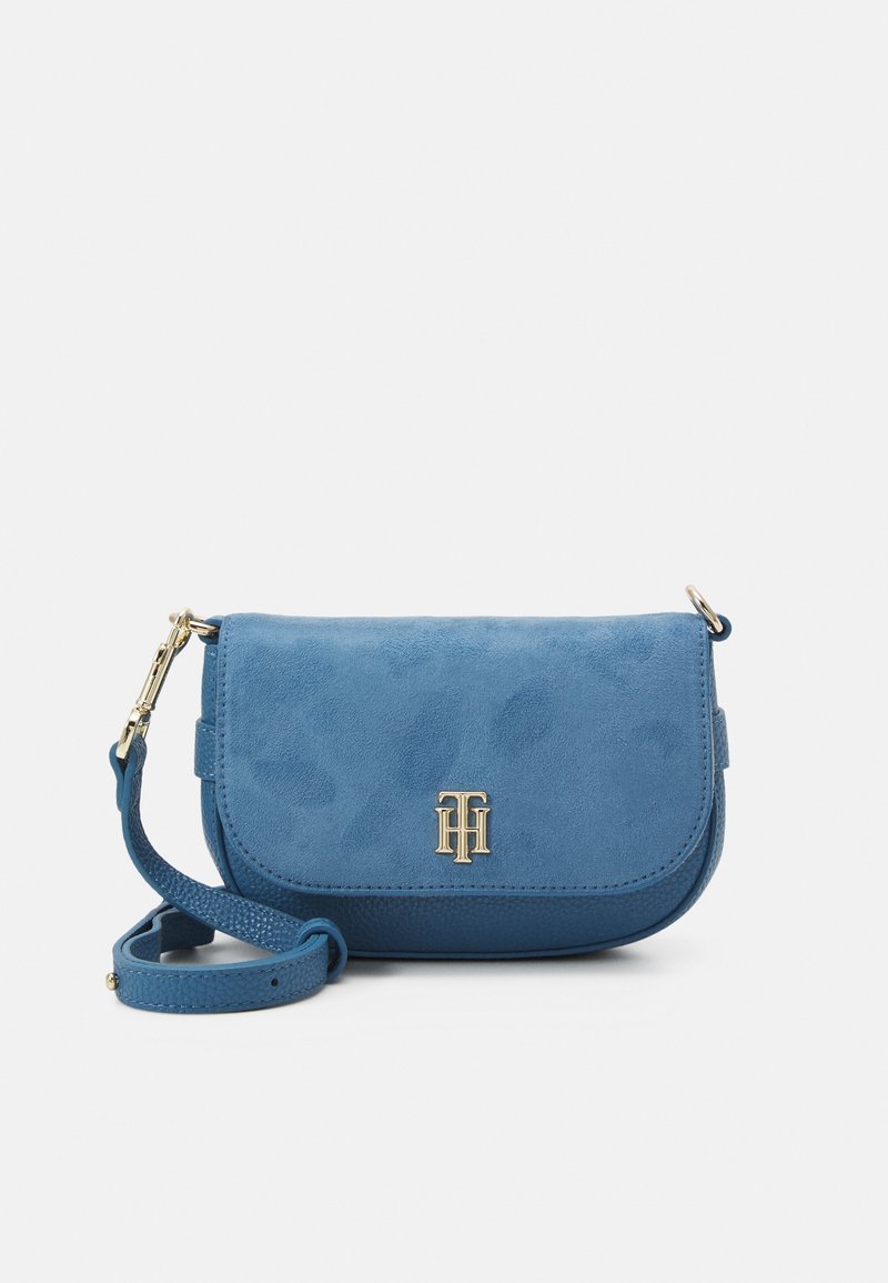 Blue suede crossbody bag with a gold logo, flap closure, and a textured strap. Features smooth and soft surface details.