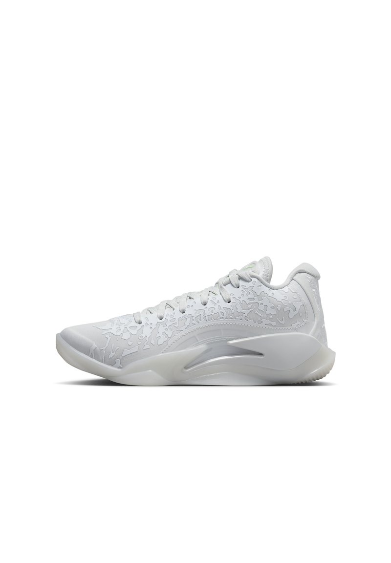 Chaussure de sport blanche avec une tige texturée, un système de laçage et une semelle lisse. Présente un motif subtil et un talon moulé pour le soutien.