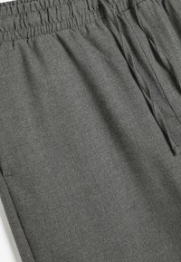 Joggers grises hechos de una tela suave, con una cintura elástica, cierre de cordón y una textura lisa en toda su superficie.