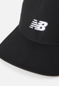 Cappellino da baseball nero con visiera curva, caratterizzato da un logo New Balance bianco sul pannello anteriore.