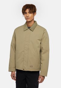 Khaki insulated jacket with a textured green collar, front snap closure, and side pockets. Features a small logo on the lower front.