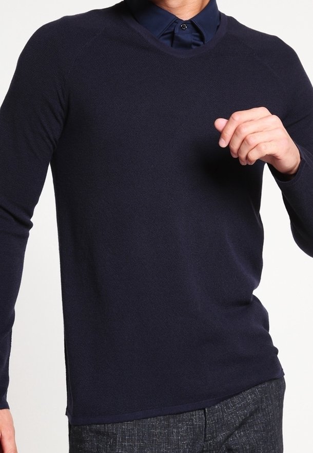 Suéter de punto azul marino de manga larga y cuello redondo, que presenta un patrón texturizado y aberturas laterales para facilitar el movimiento.