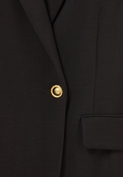 Blazer negro con tejido texturizado, cuello de muesca, un bolsillo y un botón dorado con diseño circular y acento de perla.