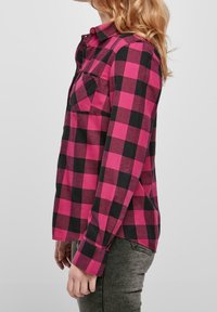 Rutigt flanellskjorta i rosa och svart. Långa ärmar, knapprad framtill och en bröstficka. Mjuk textur med avslappnad passform.