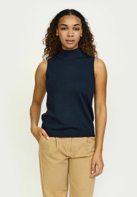 Haut sans manches gris marine en tricot côtelé, avec un design ajusté et une légère extensibilité, associé à un pantalon beige clair.