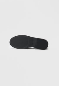 Black rubber sole with textured grip pattern and a rounded shape. Material appears flexible with a smooth finish. No visible markings.