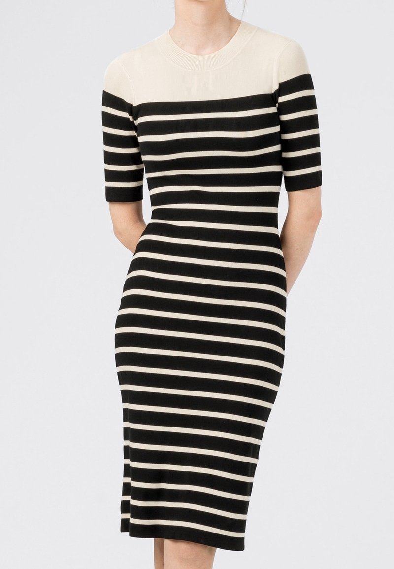 Robe en tricot rayée noire et beige avec des manches courtes, un col rond et une coupe ajustée. Contient des poches latérales. Texture lisse.