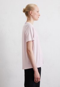 Lichtroze katoenen t-shirt met korte mouwen en een relaxte pasvorm. Ronde halslijn, soepele textuur en licht gebogen onderrand.