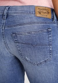 Blaue Jeans aus Denim mit einem verblassten Waschung, klassischem Fünf-Taschen-Design und einem geprägten Leder-Patch am hinteren Bund mit Zierstichen.