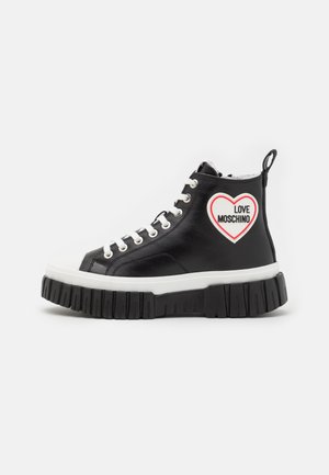 Czarny sneaker na wysokiej platformie z białą podeszwą, białymi sznurówkami i naszywką w kształcie serca z napisem „LOVE MOSCHINO” po stronie kostki.