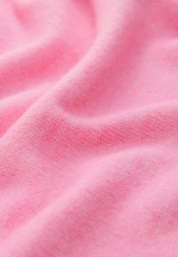 Tela rosa suave que muestra una superficie lisa y texturizada con un sutil patrón de punto, cayendo en pliegues suaves.