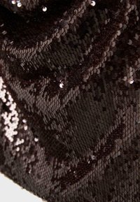 Tissu noir densément recouvert de petites paillettes brillantes, créant une surface réfléchissante et texturée.