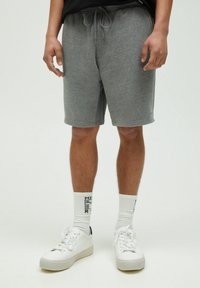 Shorts en mélange de coton gris avec un waistband élastique et un cordon de serrage. Associés à des baskets blanches et des chaussettes à motifs. Coupe décontractée.