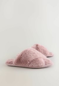 Roze pluizige slippers met een kruislings ontwerp, zachte textuur en een platte zool. Het materiaal lijkt luxe met een lichte glans.