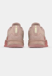 Roosa sportjalatsite paar, vaadatuna tagantpoolt, millel on täpilised keskmised taldad ja beežid tõmmisribad, millest üks kannab vertikaalset triipu ja teksti "20".