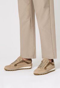 Sneaker in suede beige con pannello laterale a stampa leopardata, dotati di chiusura con lacci e suola in gomma texturizzata. Progettati per comfort e supporto.