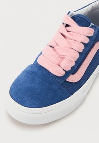 Blå mockasneakers med rosa snören och sidoprydnader. Har rund tå och vit gummisula. Närbild av ovandelsdesignens detaljer.