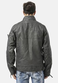 Schwarze Leder-Motorradjacke mit strukturierten Akzenten, gesteppte Schultern und eingeprägtem Logo auf der Rückseite. Ausgestattet mit Reißverschlüssen und Schnallendetails.