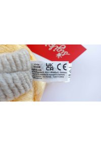 Clothing label showing UKCA and CE marks, product codes, manufacturer in Germany, eco-friendly note, and "made in China" text on soft fabric.
