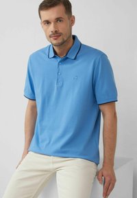 Hellblaues Polohemd mit einer Knopfleiste mit zwei Knöpfen, kontrastierendem dunklem Kragenbesatz und Logodetail auf der linken Seite. Aus Baumwollmaterial.