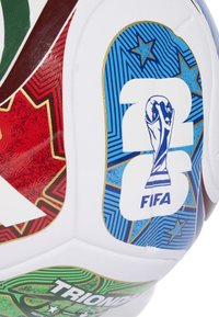 Detailný záber na časť futbalovej lopty FIFA World Cup 2023 s farebnými hviezdami v červenej, modrej a zelenej farbe na bielom pozadí.