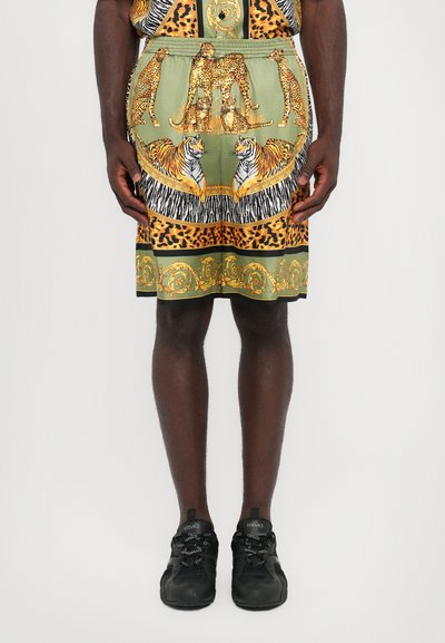 Shorts verts à motifs avec des léopards et des tigres, mêlant imprimés animaliers et accents dorés, finis avec une taille élastique.