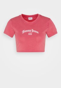 Zkrácené růžové tričko z jemné bavlny, které má kulatý výstřih a bílou logo "Tommy Jeans" vyšívané na přední straně. Krátké rukávy.
