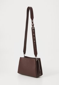 Borsa a spalla in pelle marrone texture con chiusura a zip, base piatta e tracolla regolabile con hardware in argento e dettagli a bottone.