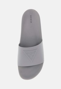 Chausson en caoutchouc gris avec une large lanière arborant un logo triangulaire. Surface lisse et mate avec une texture subtile et une conception de orteil arrondi.