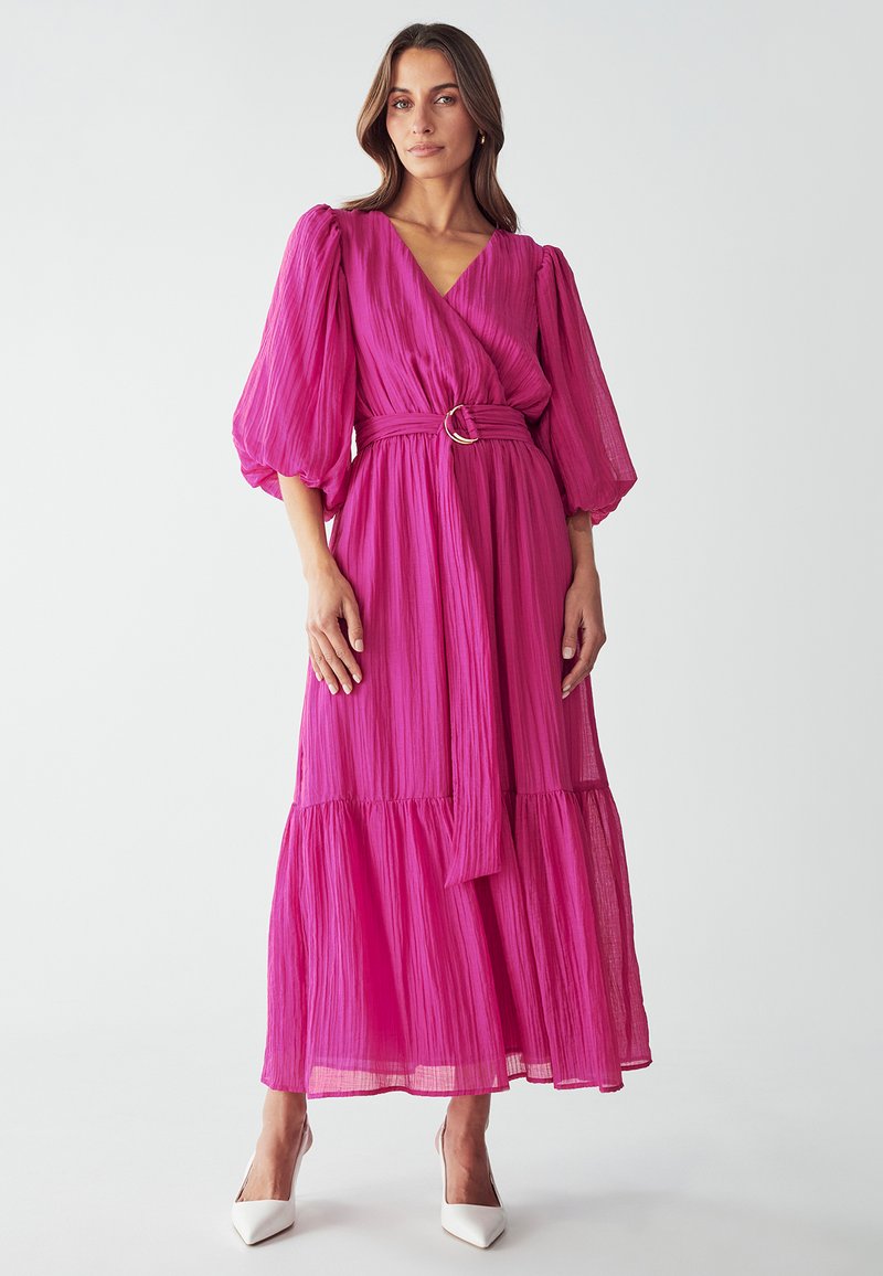Lang, plissiertes Kleid in leuchtendem Pink mit Wickeldesign, das in der Taille mit einer runden Schnalle gegurtet ist. Es hat Puffärmel und einen gestuften Saum.