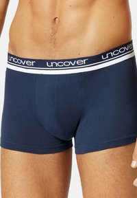 Marineblauwe boxershorts van een gladde stof, met een comfortabele tailleband voorzien van het witte "uncover" logo en twee witte strepen.