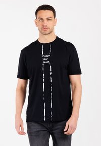 Camiseta negra de manga corta y cuello redondo. Presenta el texto blanco "Protege tu paz" centrado verticalmente con dos rayas verticales similares a pintura.