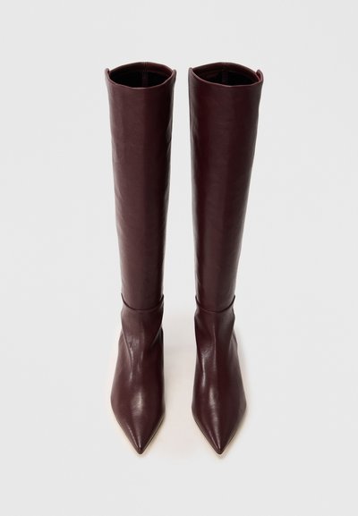 Knee-high, bordeauxleren laarzen met een puntige neus en een gladde textuur. Aansluitend ontwerp met een subtiele plooival nabij de enkel.