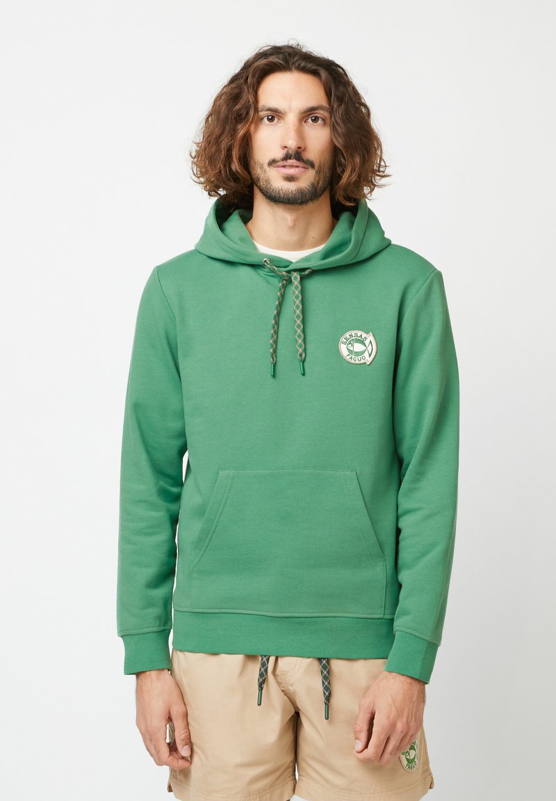 Green hoodie made of cotton, featuring a front kangaroo pocket, adjustable drawstring hood, and a circular graphic logo on the chest.