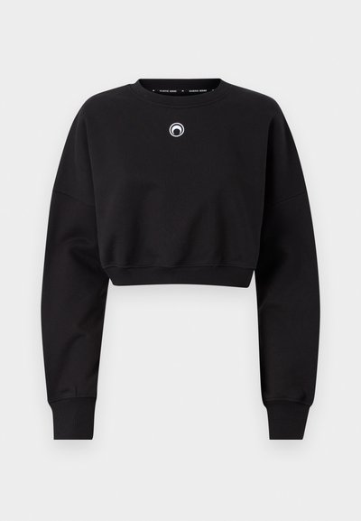 Svart, cropped sweatshirt laget av mykt stoff. Har lange ermer, rund hals, og en liten logo på brystet. Ribbestrikket mansjetter.