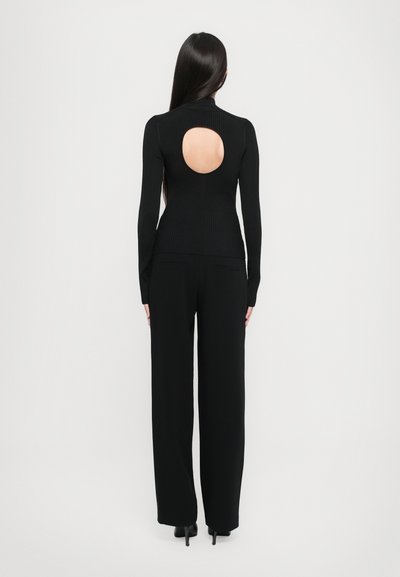 Top negru cu dungi, pe mânecă lungă, dotat cu o decupare rotundă în spate, asortat cu pantaloni negri cu croi larg. Textură netedă; design ajustat.