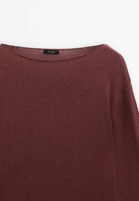 Pull tricoté marron avec un large col rond, montrant un tissu texturé et une étiquette noire cousue à l'intérieur du col.