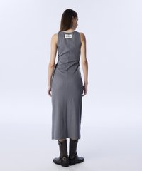 Vestido gris sin mangas con una silueta ajustada, de largo a la rodilla, que presenta una etiqueta en la parte posterior y lazos laterales. Combinado con botas negras hasta el tobillo.