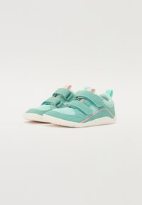 Türkiissinised sneakers, millel on võrgust ülemine osa, kaks reguleeritavat rihma ja roosa aktsent tallal. Kerged ja tekstuuriga disain.