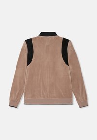 Velours jack in lichtbruin met zwarte suede schouderaccenten, geribbelde zwarte kraag en een plain achterkant. Zachte textuur, casual pasvorm.