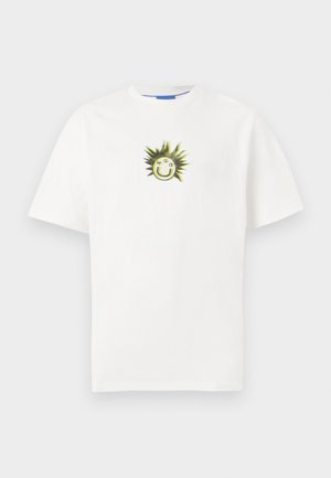 T-shirt bianco in cotone con una grafica di una faccina sorridente circondata da punte verdi. Maniche corte e collare rotondo.