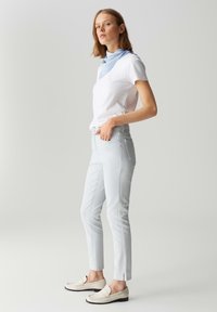 Lichtblauwe slim-fit broek van katoenmix, met zijzakken en ventilatiedetails aan de zoom. Gepaard met een wit t-shirt en instappers.