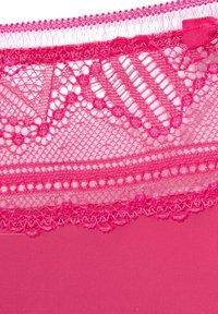 Rozā mežģīnes apdare ar ziedu rakstiem un maziem punktiņiem uz vienkrāsaina rozā auduma. Mežģīnēm ir viļņveida malas un maiga tekstūra.