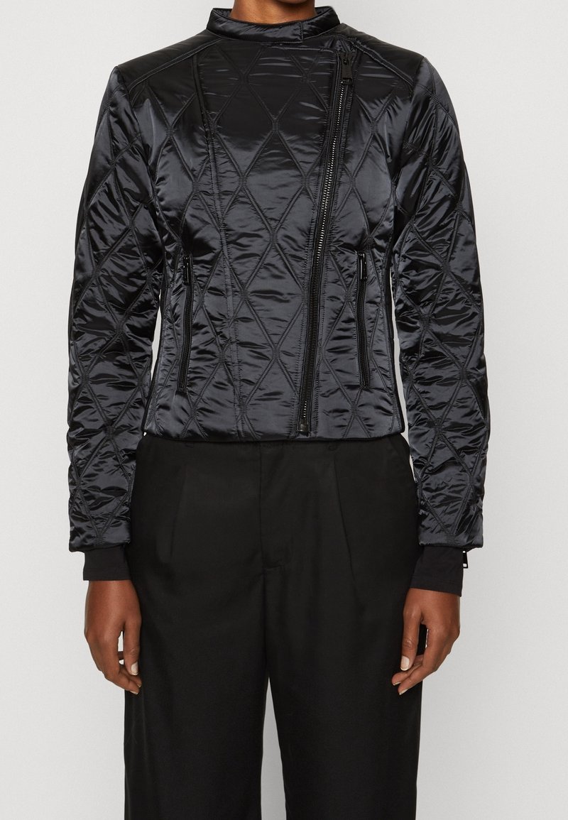 Black quilted bomber jacket with a high collar, zip closure, and two side pockets. Features a smooth texture and elastic cuffs.