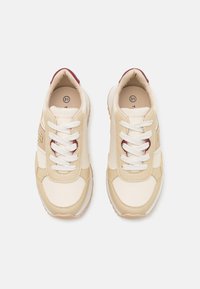 Sneakers beige con accenti crema, tomaia texturizzata, lacci bianchi e dettaglio in bordeaux sul tallone. Punta arrotondata e suola imbottita per il comfort.