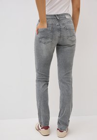 Grijze denim jeans met een slim fit, voorzien van achterzakken en een licht vervaagde afwerking. Enkel lengte met minimale stikdetails.
