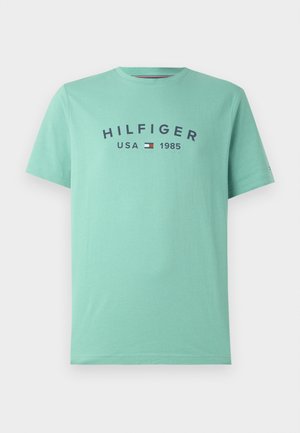 Tricou mint verde din bumbac moale, cu guler rotund, mâneci scurte și un grafic pe față cu "HILFIGER USA 1985" în albastru marin.