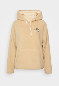 Beige fleece hoodie with a front pocket, drawstrings, and a diamond logo patch. Features a hood and a soft, textured finish.